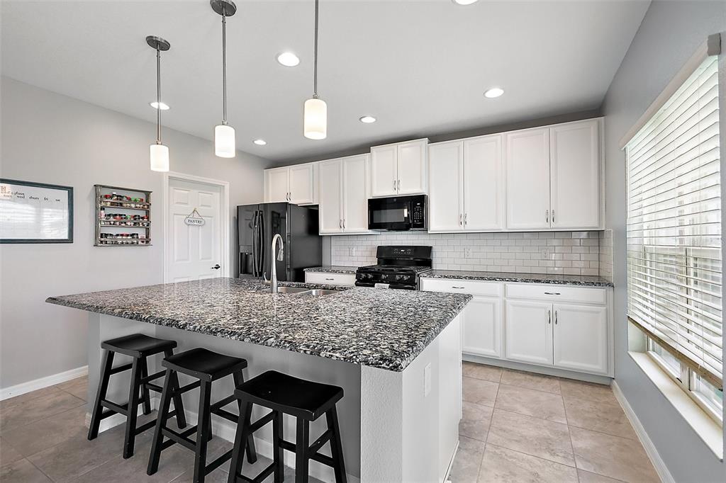 1292 Cavender Creek Road Minneola, FL 34715 - Photo 11 of 36 a kitchen with kitchen island granite countertop a sink a center island and stainless steel appliances