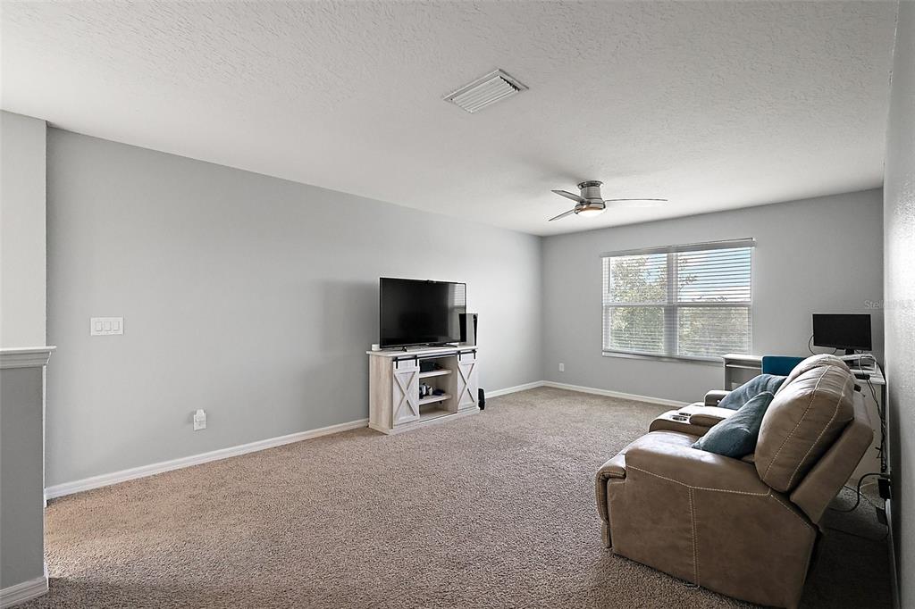 1292 Cavender Creek Road Minneola, FL 34715 - Photo 26 of 36 a living room with furniture and a flat screen tv