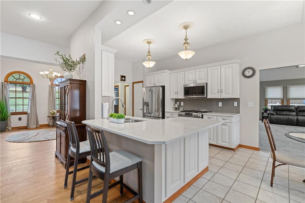 2108 Mickanin Road Irwin, PA 15642 - Photo 8 of 31 a kitchen with stainless steel appliances kitchen island granite countertop a stove a refrigerator a oven a dining table and chairs with wooden floor