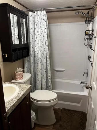 a bathroom with a granite countertop bathtub sink vanity mirror and toilet
