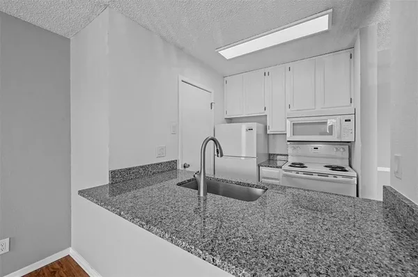 a kitchen with granite countertop a sink and a stove top oven