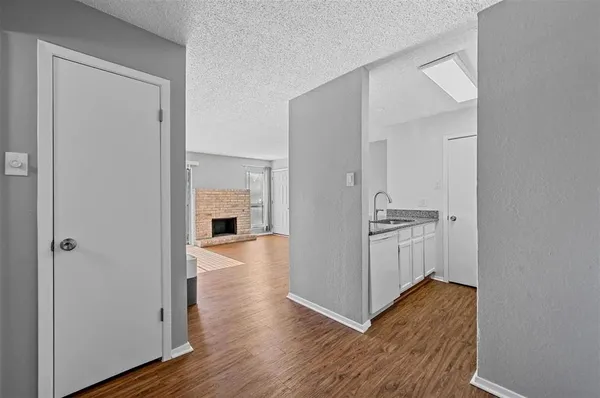 a view of a hallway with wooden floor and a bathroom