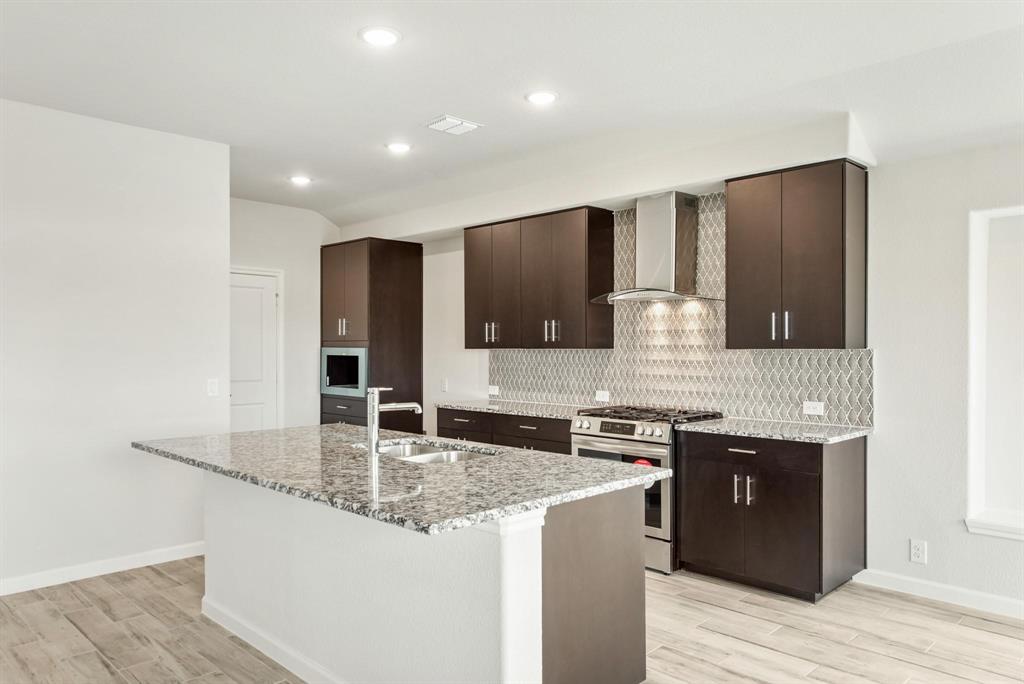 920 Elk Ridge Run Godley, TX 76044 - Photo 16 of 34 Modern kitchen featuring a central island with a double basin sink and a granite countertop
