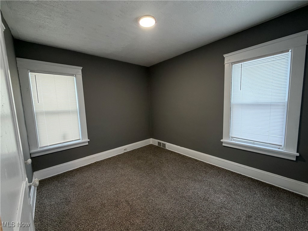 16309 Nela View Road Cleveland, OH 44112 - Photo 10 of 29 Empty room with dark colored carpet and a textured ceiling