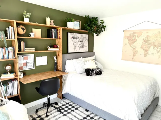 a bedroom with a bed a dresser and potted plant