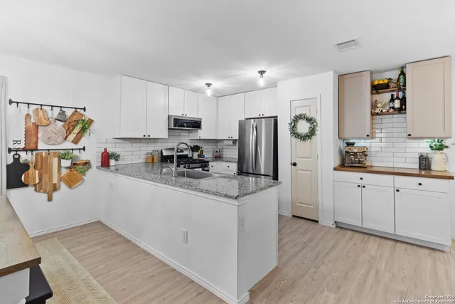 a kitchen with stainless steel appliances kitchen island granite countertop a dining table chairs and a refrigerator