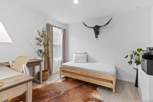 a bedroom with a bed and a potted plant on the dresser