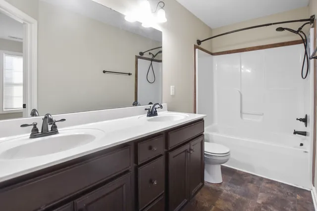 a bathroom with a double vanity sink toilet mirror and bathtub