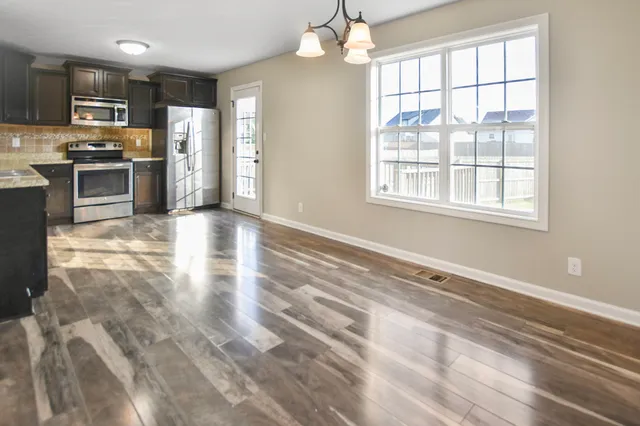 a view of kitchen with stainless steel appliances wooden floor and large window