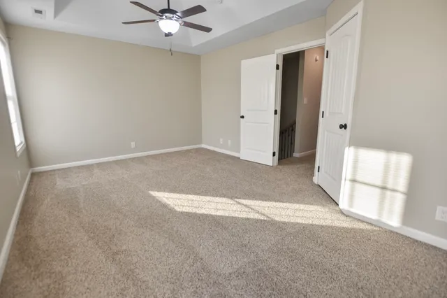 an empty room with a ceiling fan and window