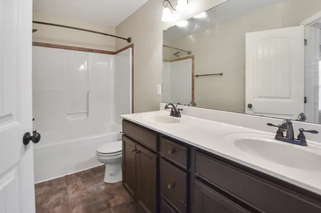 a bathroom with a double vanity sink toilet mirror and shower