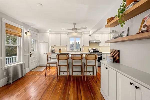 a dining hall with stainless steel appliances granite countertop a stove a sink dishwasher and a dining table with wooden floor