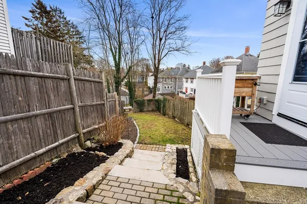 a view of backyard with wooden fence and large trees