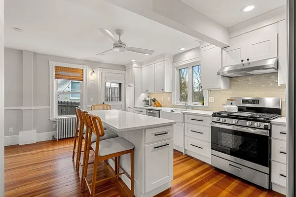 a kitchen with stainless steel appliances a stove a sink cabinets and wooden floor