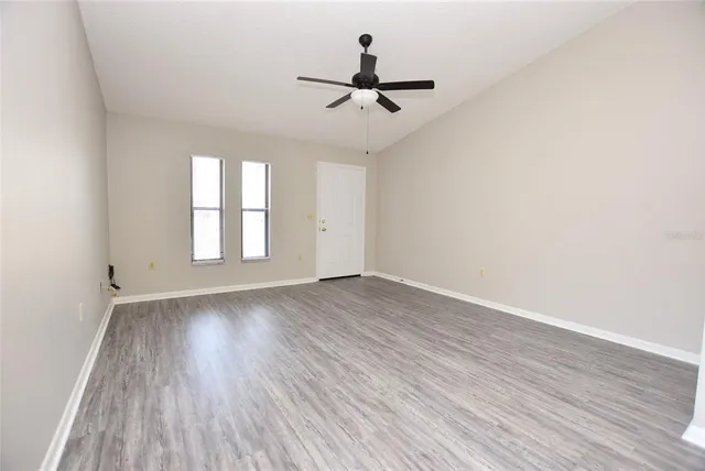 a view of empty room with wooden floor and fan