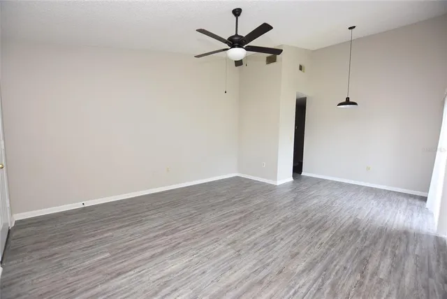 a view of a room with wooden floor and a ceiling fan