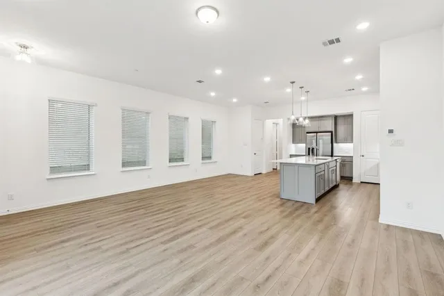 a large white kitchen with kitchen island a sink wooden floor stainless steel appliances and cabinets