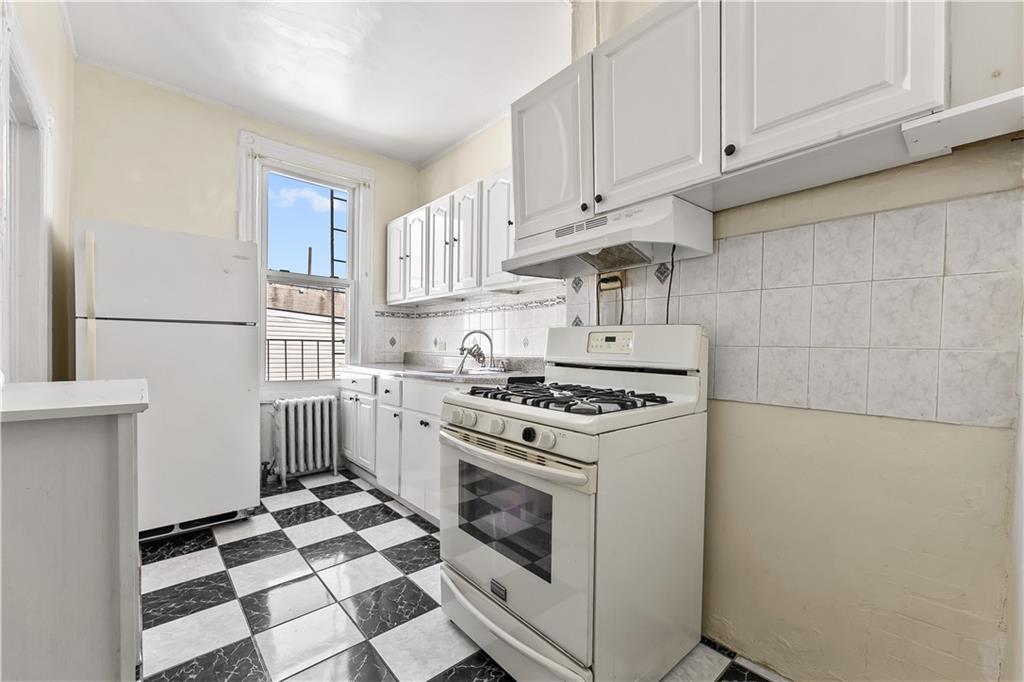 1271 Bushwick Avenue Brooklyn, NY 11207 - Photo 7 of 13 a kitchen with cabinets and white appliances