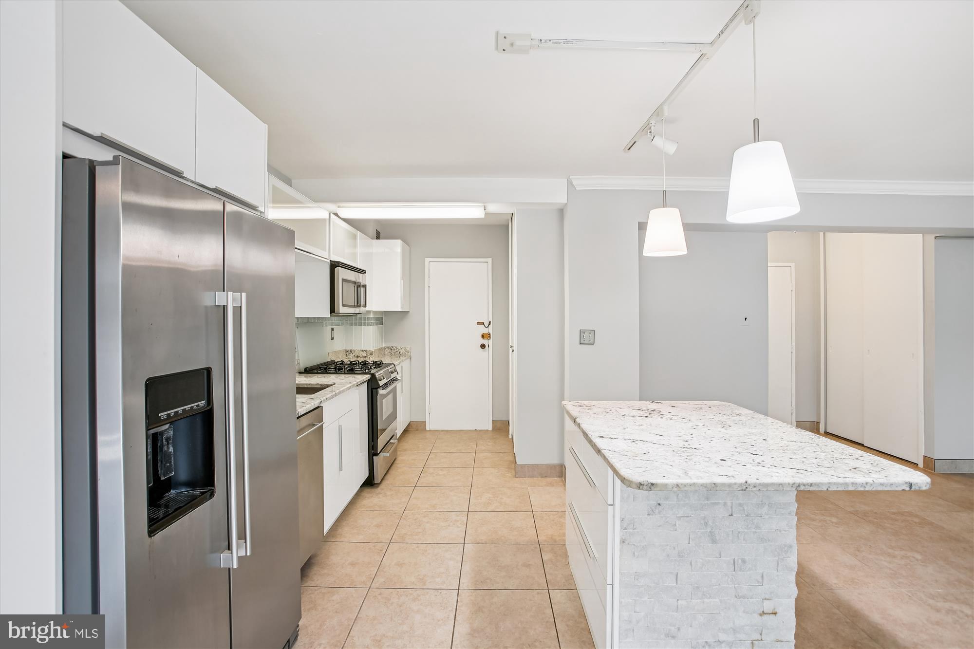 4201 Cathedral Avenue Northwest, Unit 407W Washington, DC 20016 - Photo 15 of 54 a kitchen with stainless steel appliances kitchen island granite countertop a refrigerator and a sink