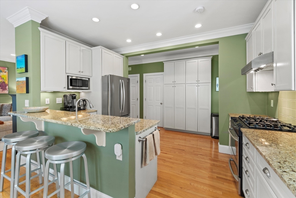 3 A Mill Street, Unit 3A Arlington, MA 02476 - Photo 7 of 38 a kitchen with kitchen island granite countertop a sink a stove a refrigerator cabinets and wooden floor
