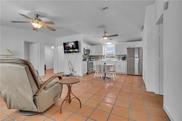 a kitchen with stainless steel appliances granite countertop a refrigerator a stove a sink dishwasher and white cabinets with wooden floor