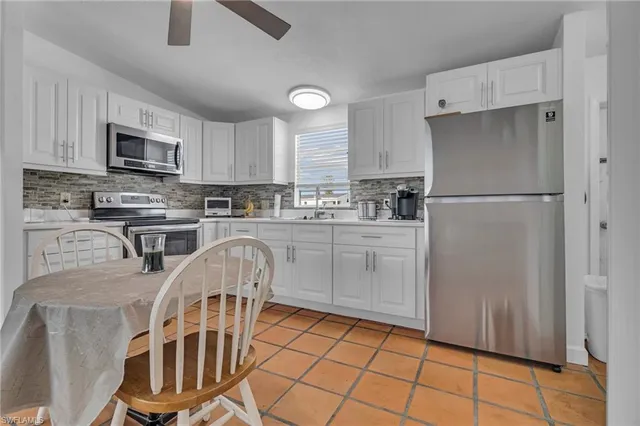 a kitchen with stainless steel appliances granite countertop a stove a sink dishwasher a refrigerator and white cabinets with wooden floor