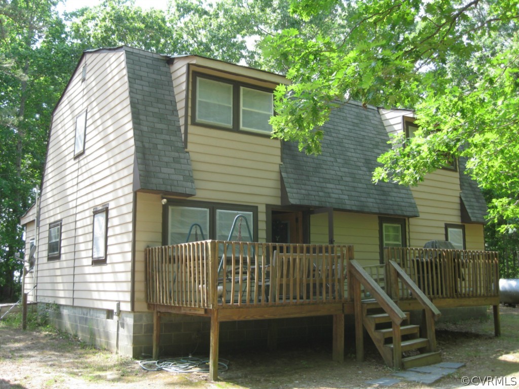 a view of a house with a wooden deck and a floor to ceiling window