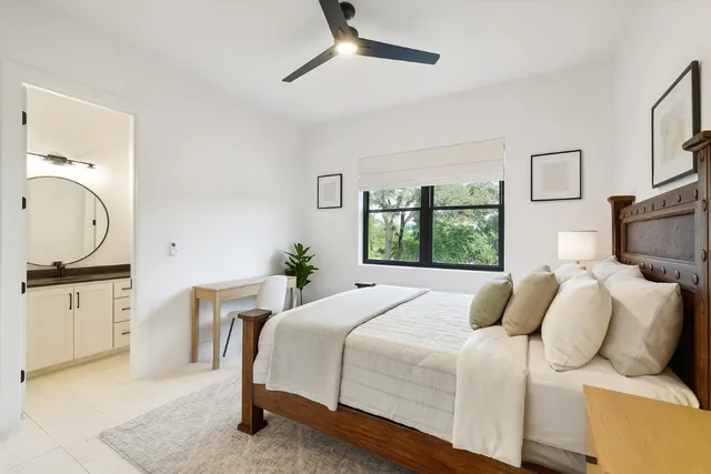 a bedroom with a bed a window and potted plant on the dresser