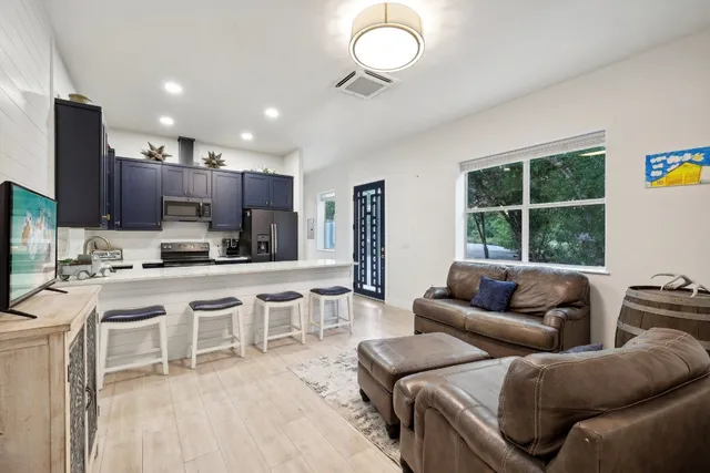 a living room with stainless steel appliances kitchen island granite countertop furniture and a large window