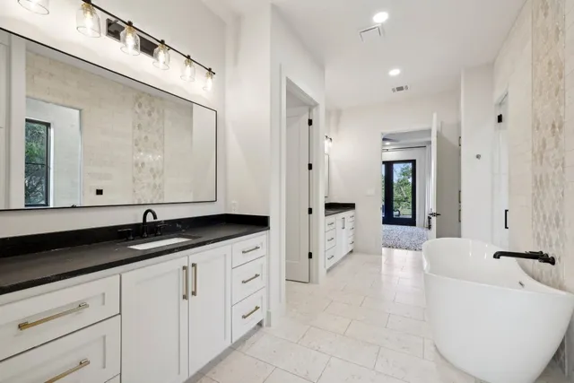 a spacious bathroom with a granite countertop tub sink and mirror