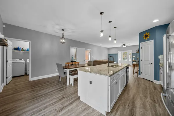 a kitchen with stainless steel appliances granite countertop a refrigerator a stove oven a sink dishwasher and white cabinets with wooden floor