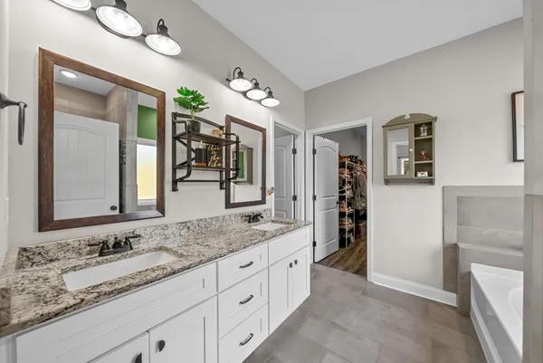 a bathroom with a granite countertop double vanity sink and a mirror