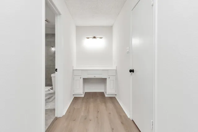 a view of a hallway with wooden floor and a bathroom
