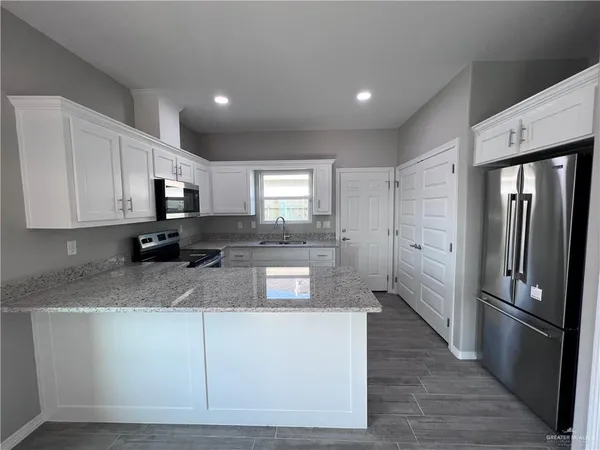 a kitchen with stainless steel appliances granite countertop a refrigerator a stove a sink and a microwave