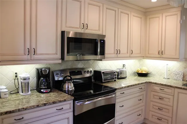 a kitchen with granite countertop white cabinets and stainless steel appliances
