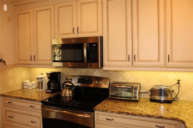a kitchen with granite countertop white cabinets and stainless steel appliances