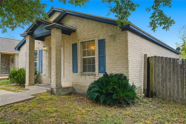 a view of a house with small yard plants and a lawn chairs