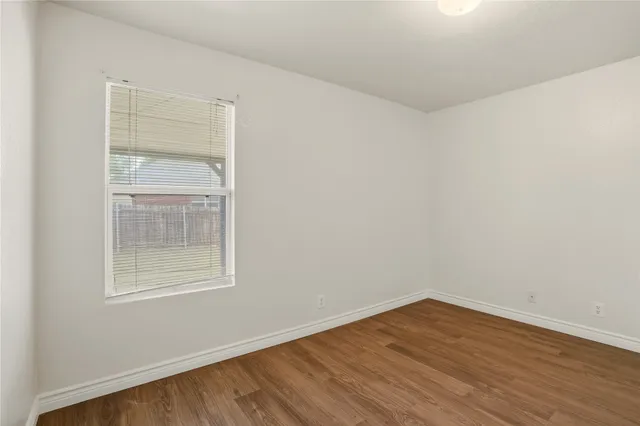 an empty room with wooden floor and fan