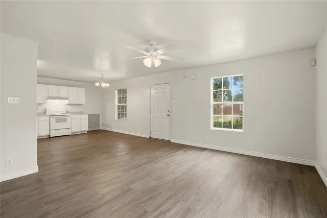 a view of an empty room with a window and wooden floor