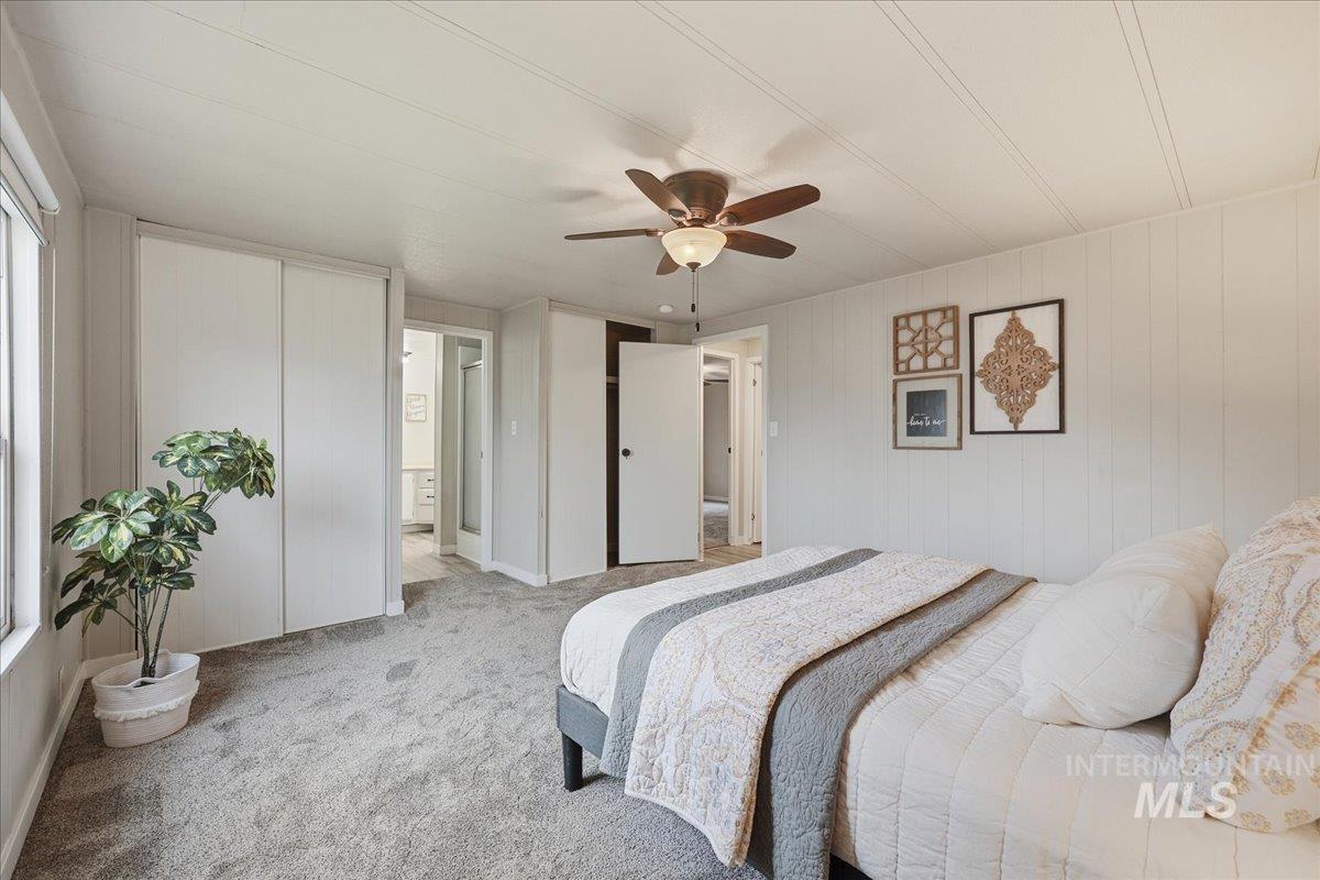 445 South Maple Grove Road, Unit 15 Boise, ID 83709 - Photo 11 of 20 Carpeted bedroom with a closet, a ceiling fan, and wood walls