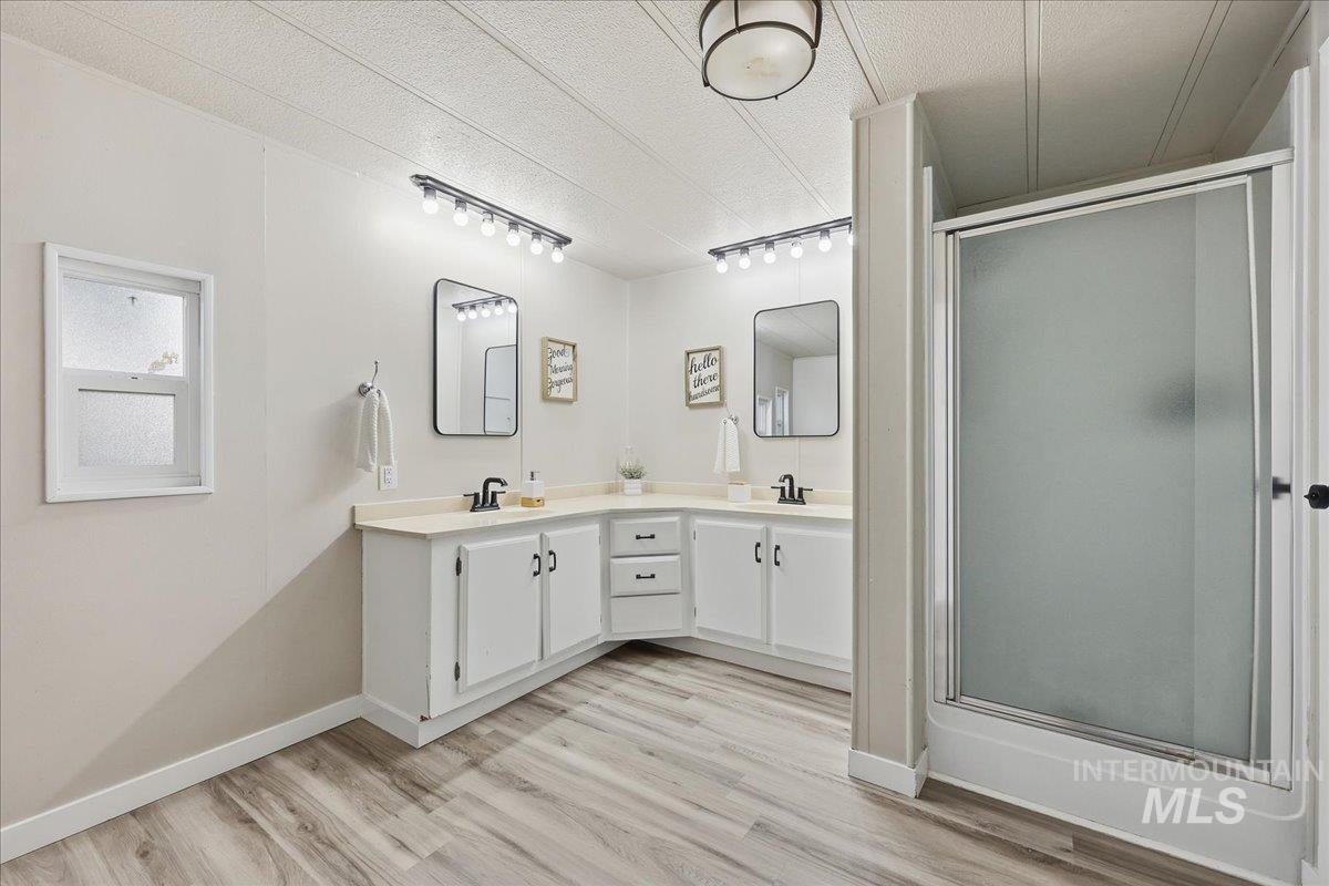 445 South Maple Grove Road, Unit 15 Boise, ID 83709 - Photo 12 of 20 Bathroom with double vanity, a shower stall, light wood-type flooring, track lighting, and a textured ceiling