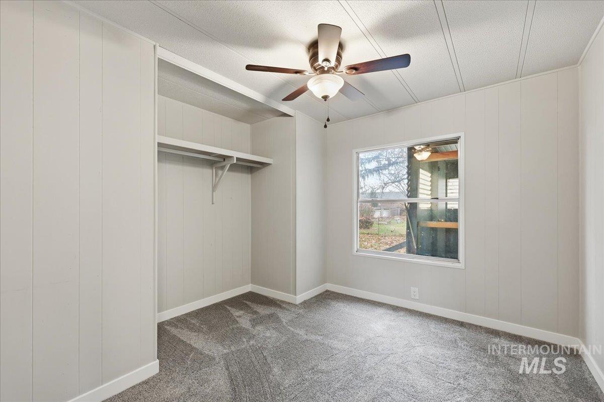 445 South Maple Grove Road, Unit 15 Boise, ID 83709 - Photo 14 of 20 Unfurnished bedroom featuring carpet flooring, wood walls, and ceiling fan