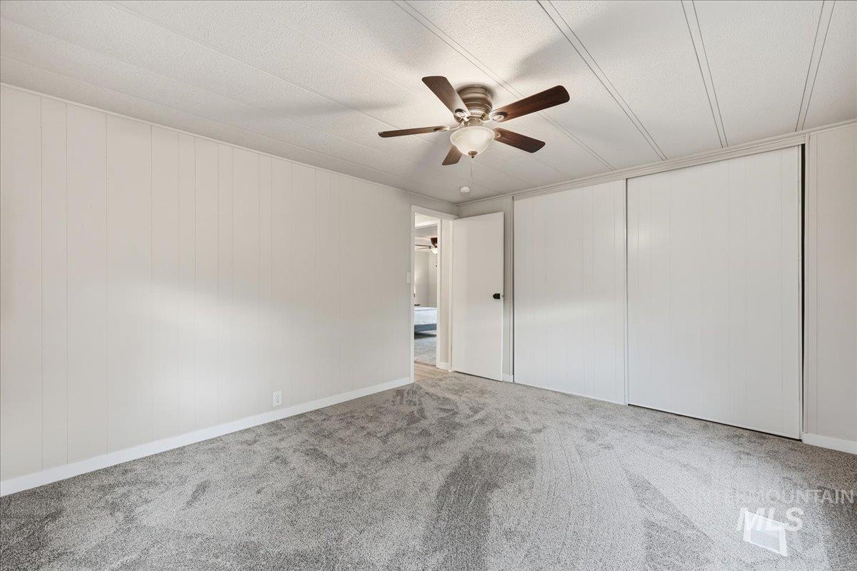 445 South Maple Grove Road, Unit 15 Boise, ID 83709 - Photo 17 of 20 Spare room with ceiling fan, carpet, and wooden walls