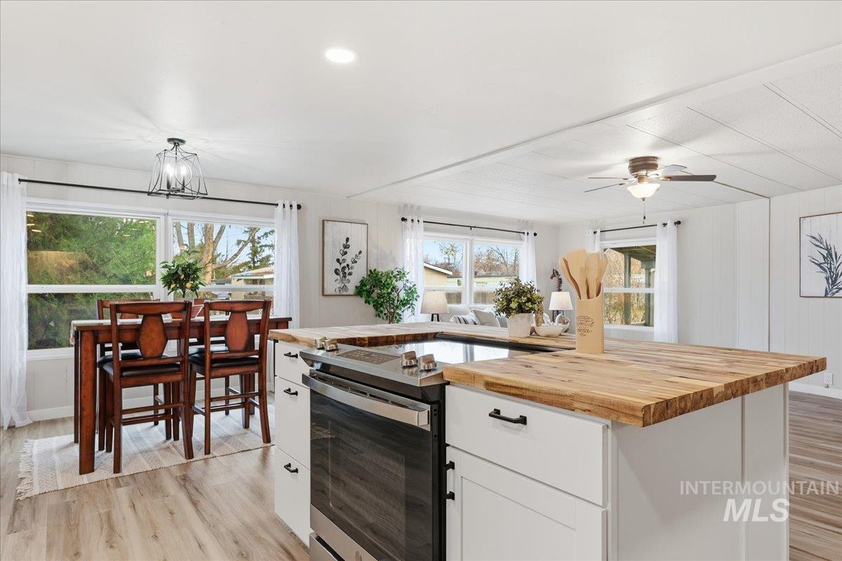 445 South Maple Grove Road, Unit 15 Boise, ID 83709 - Photo 7 of 20 Kitchen with butcher block countertops, stainless steel electric range oven, light wood-style floors, white cabinets, and a center island