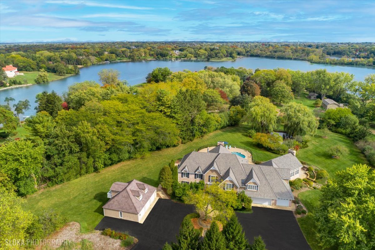 an aerial view of ocean with residential house with outdoor space and trees around