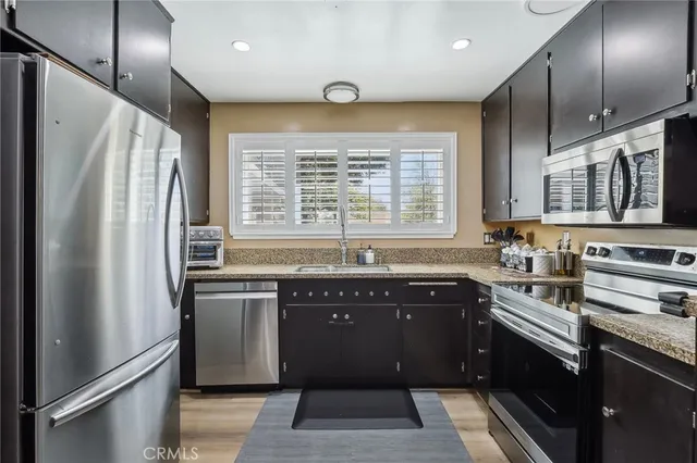 a kitchen with stainless steel appliances granite countertop a sink stove and refrigerator