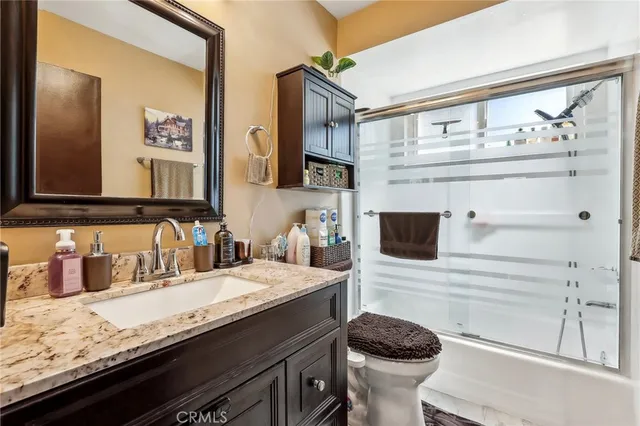 a bathroom with a granite countertop toilet sink and mirror