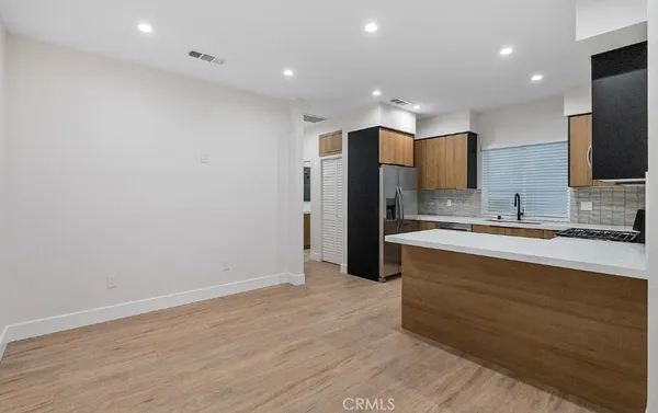 a large kitchen with stainless steel appliances a large counter top a sink and a refrigerator