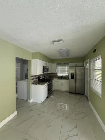 a kitchen with a refrigerator and white cabinets