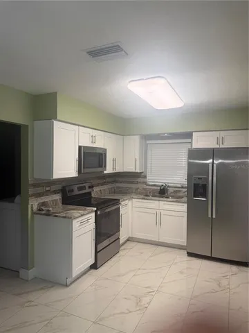 a kitchen with stainless steel appliances granite countertop a stove top oven and refrigerator